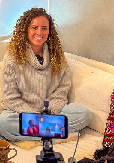 afifa sitting on a sofa with a camera pointer at her